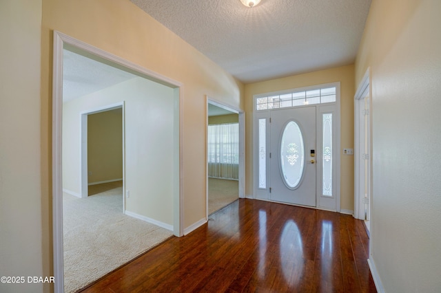 entryway with a textured ceiling, baseboards, and wood finished floors