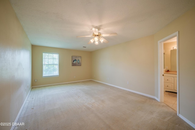 empty room with baseboards, a ceiling fan, a textured ceiling, and light colored carpet