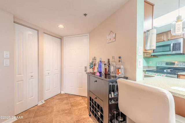 interior space featuring decorative light fixtures, light brown cabinetry, and stainless steel appliances