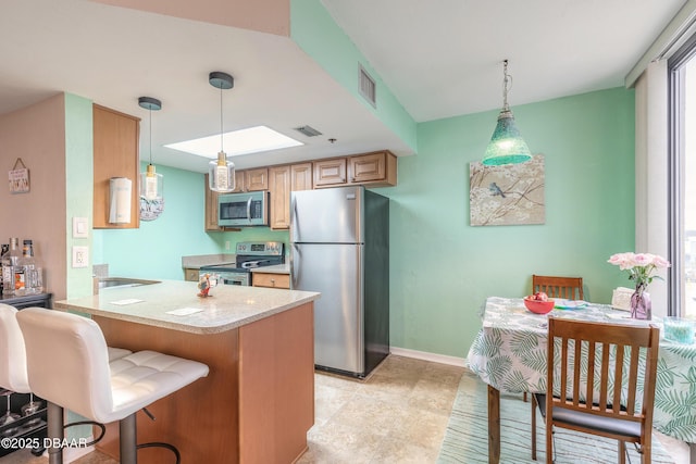 kitchen with kitchen peninsula, decorative light fixtures, a breakfast bar, and stainless steel appliances