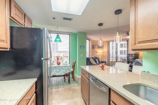 kitchen with light stone counters, pendant lighting, and appliances with stainless steel finishes