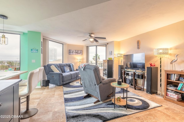 living room with ceiling fan and a wall of windows