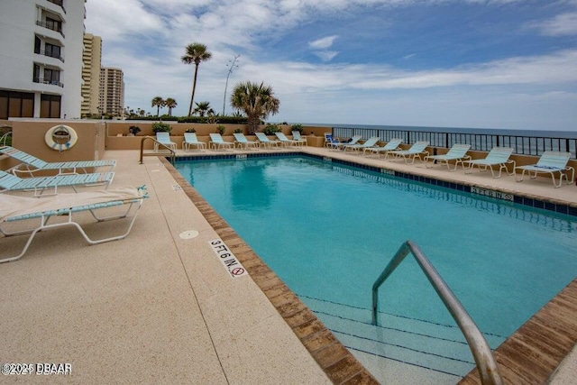 view of pool with a water view and a patio