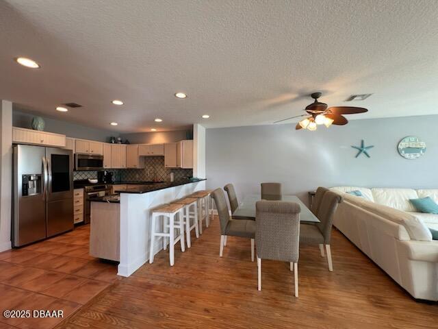 610 S Atlantic Ave, New Smyrna Beach, FL 32169 - kitchen with appliances with stainless steel finishes, a peninsula, dark countertops, open floor plan, and decorative backsplash