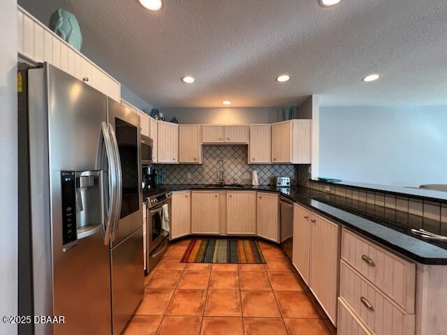 610 S Atlantic Ave, New Smyrna Beach, FL 32169 - kitchen featuring appliances with stainless steel finishes, dark countertops, light brown cabinets, decorative backsplash, and a peninsula