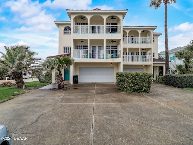 610 S Atlantic Ave, New Smyrna Beach, FL 32169 - view of front facade with ceiling fan, an attached garage, stucco siding, driveway, and a balcony