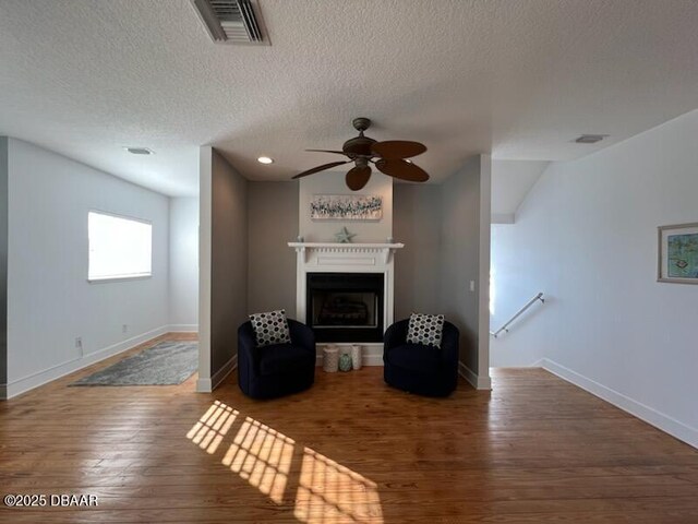 610 S Atlantic Ave, New Smyrna Beach, FL 32169 - unfurnished living room with wood finished floors, ceiling fan, a textured ceiling, baseboards, and a fireplace with raised hearth