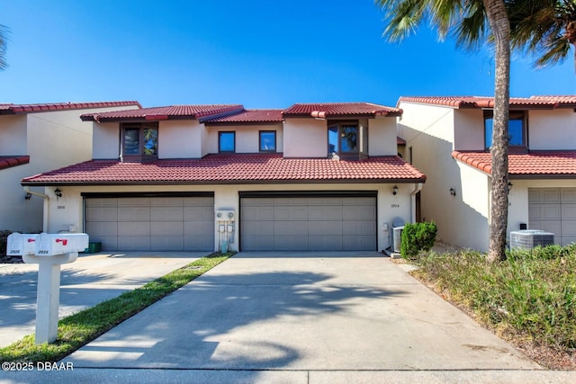 mediterranean / spanish-style house featuring a garage and central AC unit