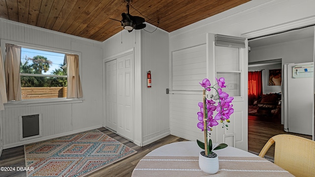 entryway with ceiling fan, wood walls, wooden ceiling, and dark hardwood / wood-style floors