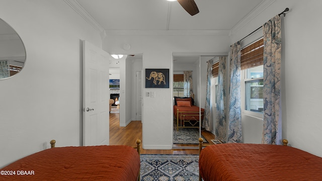 bedroom with hardwood / wood-style flooring, ceiling fan, crown molding, and a closet