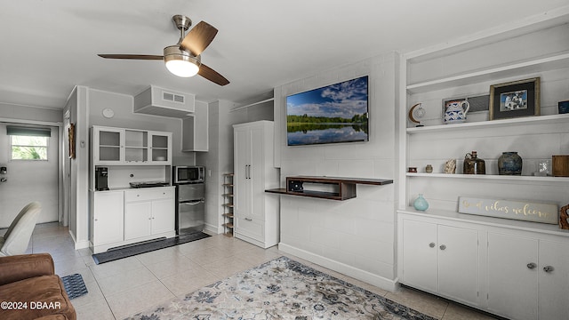 kitchen with white cabinetry, stainless steel microwave, light tile patterned floors, and ceiling fan