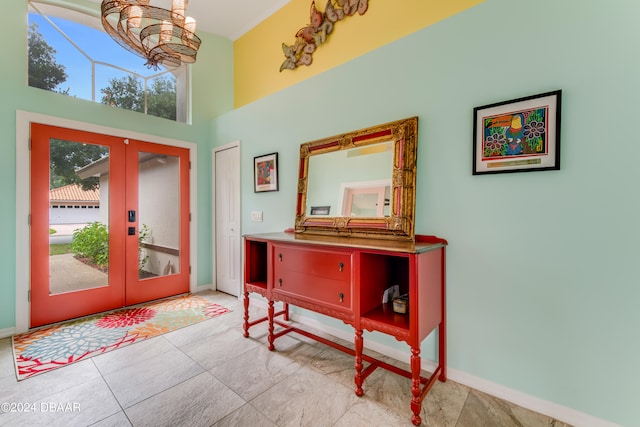 foyer entrance with a high ceiling, a chandelier, light tile patterned floors, and french doors