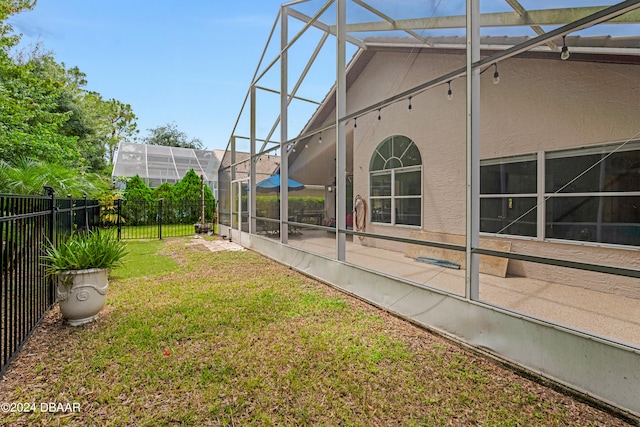 view of yard with glass enclosure and a patio