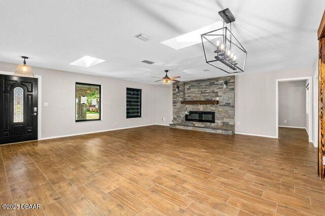 32 Twin River Dr, Ormond Beach, FL 32174 - unfurnished living room featuring visible vents, a skylight, a fireplace, baseboards, and ceiling fan with notable chandelier