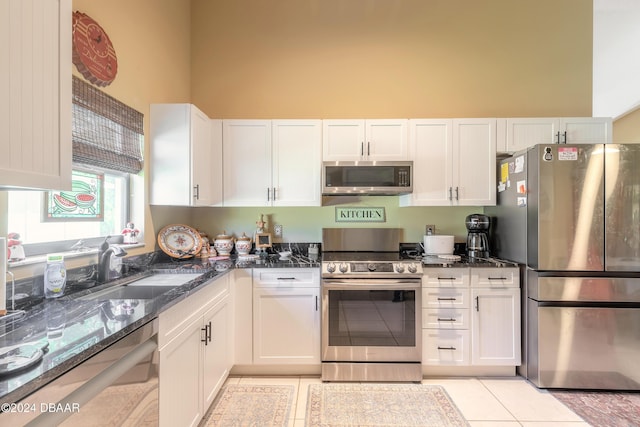 3836 Long Grove Ln, Port Orange, FL 32129 - kitchen featuring appliances with stainless steel finishes, white cabinetry, dark stone countertops, light tile patterned floors, and a towering ceiling