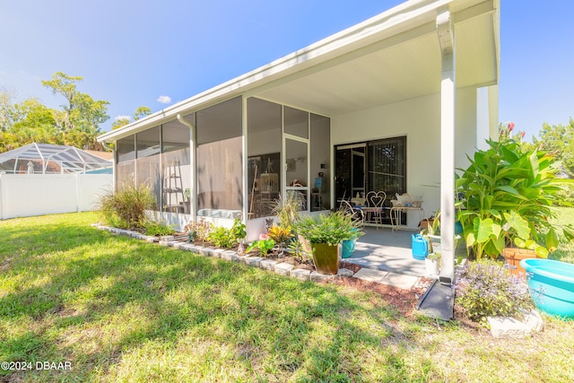 back of property with a patio area, glass enclosure, a sunroom, and a yard