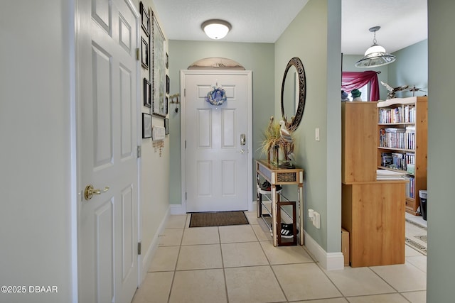 foyer featuring a textured ceiling, baseboards, and light tile patterned floors