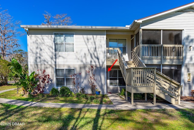 view of front of house featuring stairs, a front yard, and a sunroom