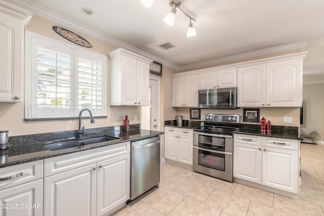 kitchen with sink, crown molding, dark stone countertops, appliances with stainless steel finishes, and white cabinets