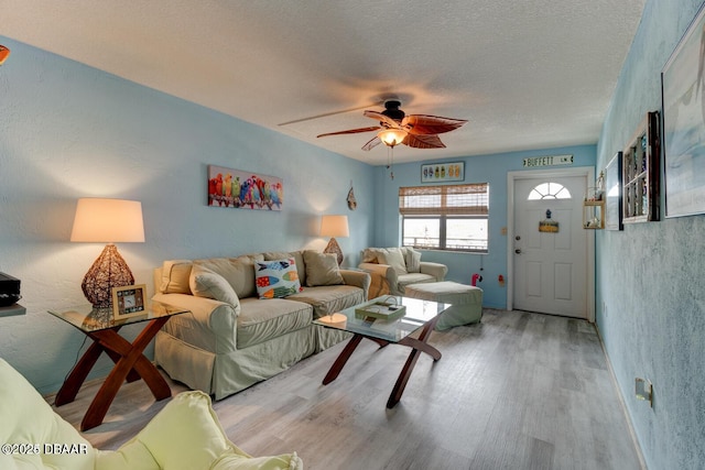 living room featuring a textured ceiling, light hardwood / wood-style floors, and ceiling fan