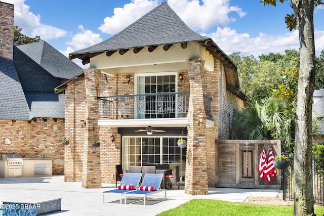 back of property with a balcony, an outdoor kitchen, ceiling fan, and a patio