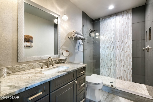 bathroom featuring vanity, tiled shower, and toilet