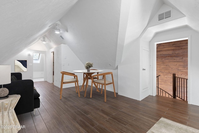 dining space featuring dark wood-type flooring and vaulted ceiling