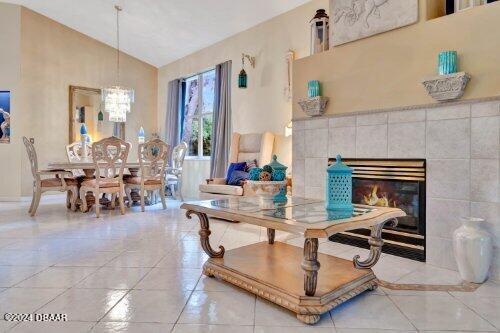 dining area with vaulted ceiling, light tile patterned floors, a fireplace, and a chandelier