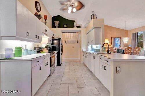 kitchen featuring stainless steel appliances, vaulted ceiling, a sink, and a peninsula