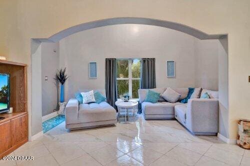 living room featuring arched walkways, plenty of natural light, and baseboards