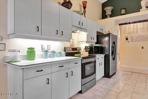 kitchen featuring white cabinets, extractor fan, stainless steel appliances, and light countertops