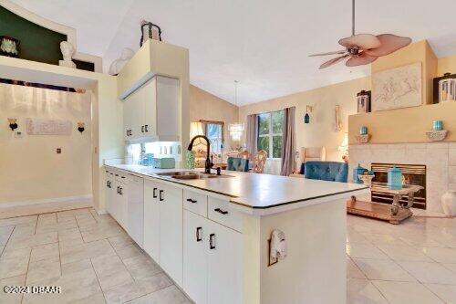 kitchen with a peninsula, vaulted ceiling, light countertops, a fireplace, and a sink