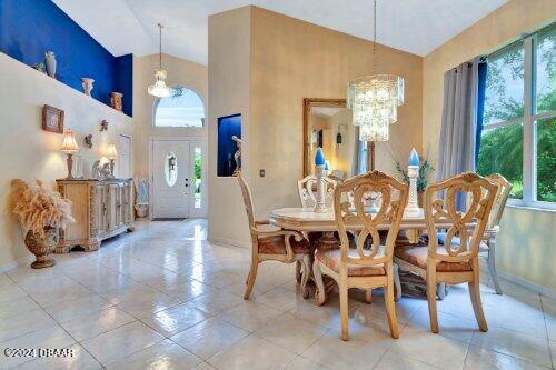 dining space with an inviting chandelier, baseboards, high vaulted ceiling, and tile patterned floors