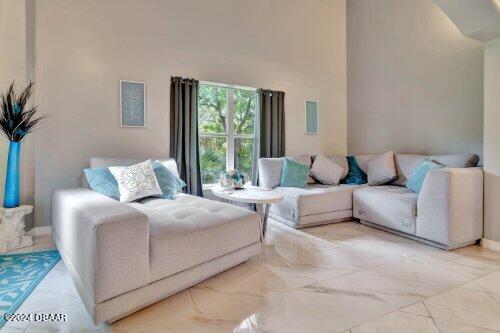 living area with marble finish floor, a high ceiling, and baseboards