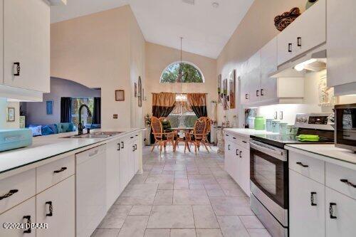 kitchen featuring light countertops, appliances with stainless steel finishes, white cabinets, a sink, and high vaulted ceiling