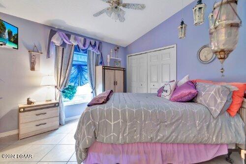 bedroom featuring baseboards, lofted ceiling, ceiling fan, tile patterned flooring, and a closet