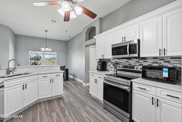 kitchen featuring tasteful backsplash, sink, white cabinets, hanging light fixtures, and stainless steel appliances