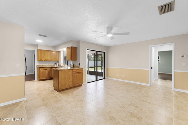 59 Blakeport Ln, Palm Coast, FL 32137 - kitchen featuring a ceiling fan, open floor plan, a peninsula, light tile patterned flooring, and brown cabinets