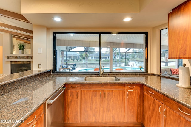 kitchen featuring dark stone countertops, a healthy amount of sunlight, sink, and dishwasher