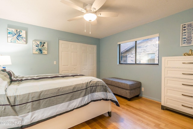 bedroom with light hardwood / wood-style floors, ceiling fan, and a closet