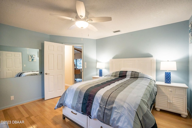 bedroom with a closet, light wood-type flooring, a textured ceiling, and ceiling fan