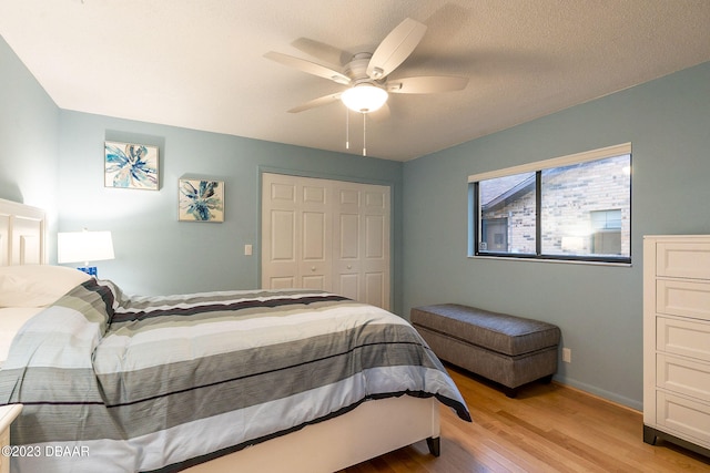 bedroom with a closet, a textured ceiling, ceiling fan, and light hardwood / wood-style flooring