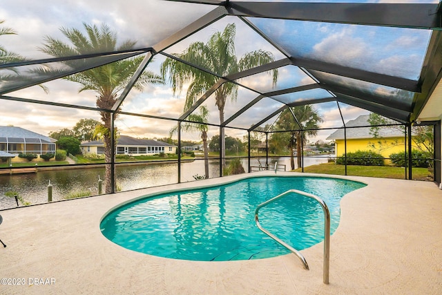 pool at dusk with a patio area, a water view, and a lanai