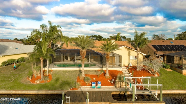 rear view of house with a lawn, a lanai, a water view, and a patio area