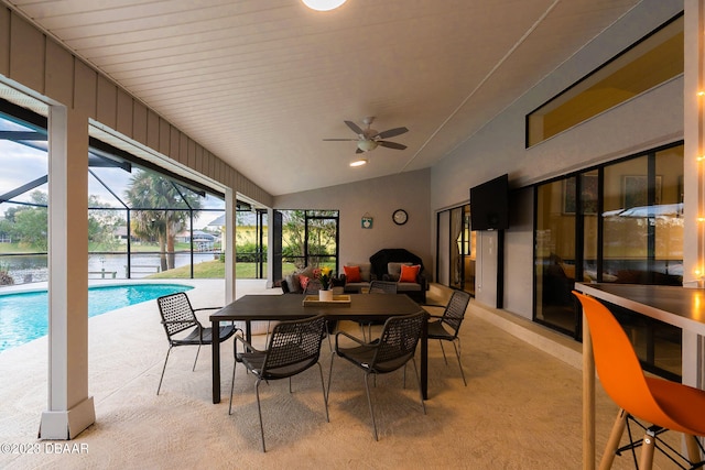 sunroom featuring a water view, lofted ceiling, ceiling fan, and a pool