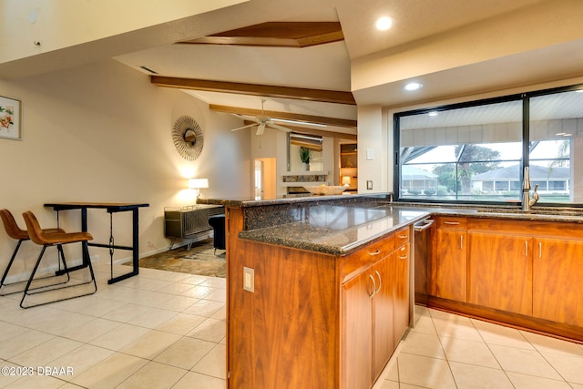 kitchen with vaulted ceiling with beams, a kitchen island, light tile patterned floors, dark stone countertops, and ceiling fan