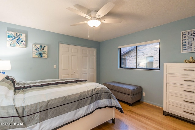 bedroom with light hardwood / wood-style floors, ceiling fan, a textured ceiling, and a closet