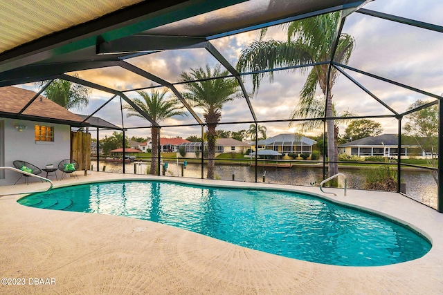 pool at dusk with a lanai, a water view, and a patio