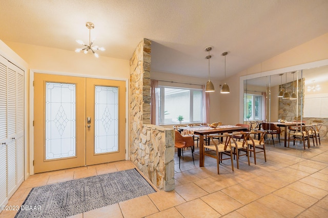 tiled entrance foyer featuring an inviting chandelier, french doors, vaulted ceiling, and a textured ceiling