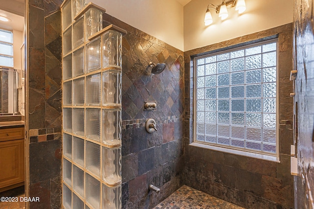 bathroom featuring vanity, a healthy amount of sunlight, and a tile shower